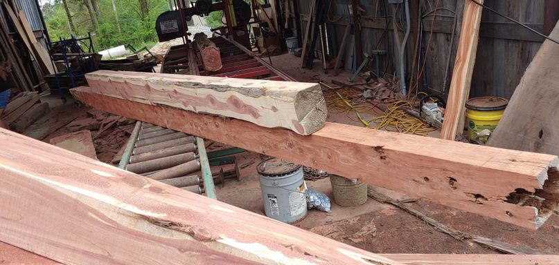 A reclaimed cedar beam being milled to spec on the on-site sawmill.